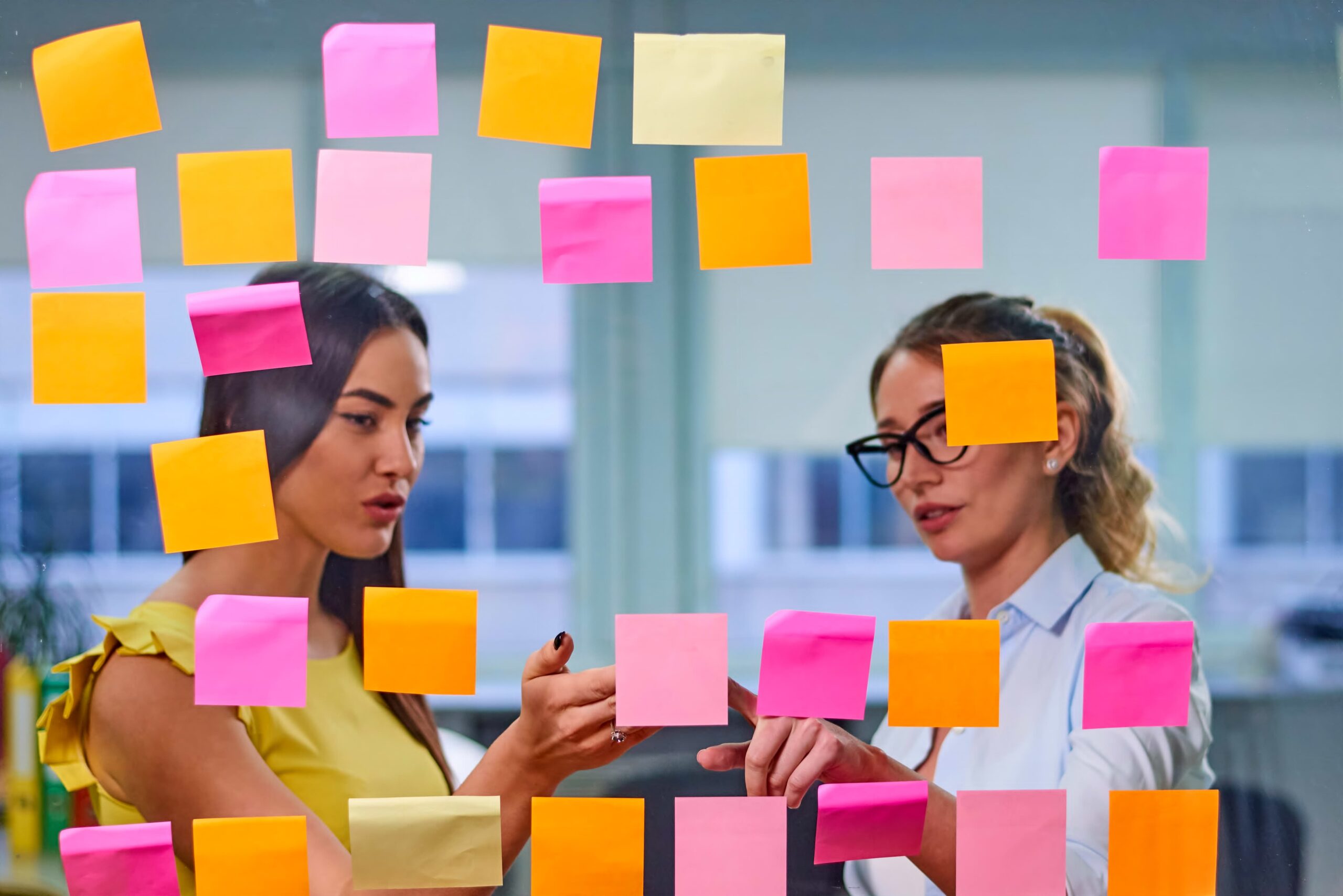 Deux collaboratrices organisent leur plan de communication interne à l'aide de post-its colorés