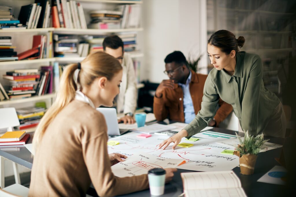 Collaboratrice pointant des éléments sur un document de planification stratégique lors d'une réunion de travail concentrée