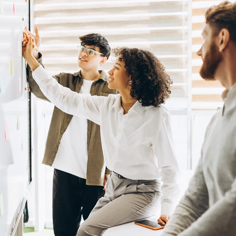 Équipe collaborant sur un plan de communication interne autour d'un tableau blanc