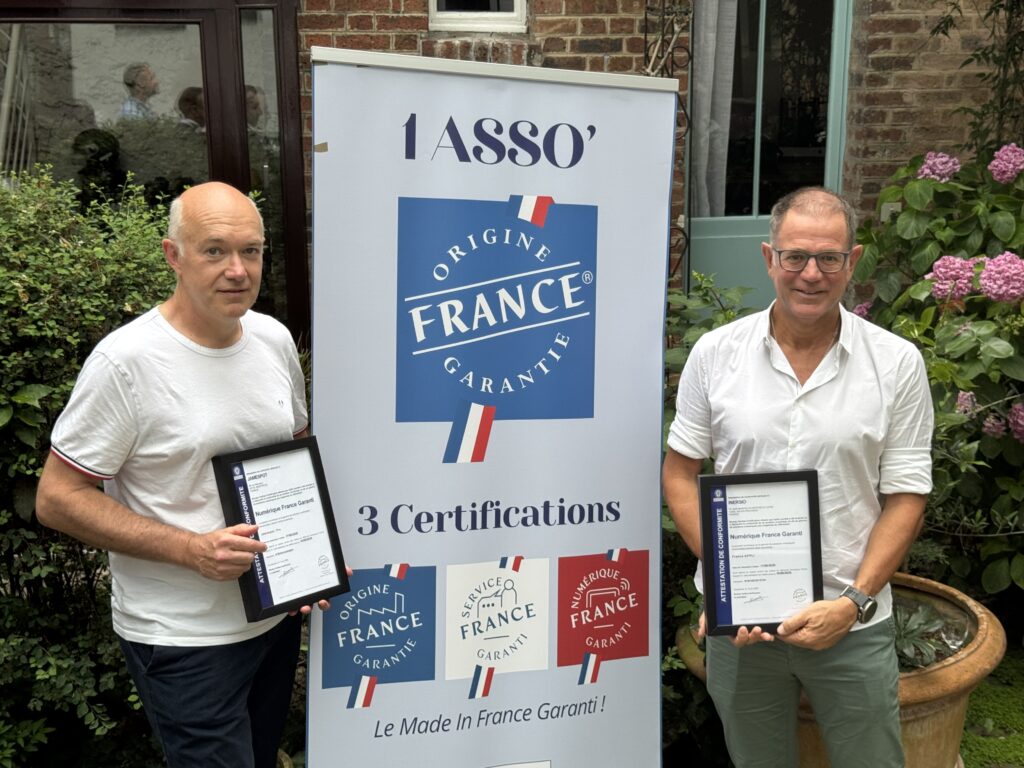 Pascal Baratoux tenant son attestation de conformité Numérique France Garanti, devant un kakémono de l'association Origine France Garantie présentant ses trois certifications.