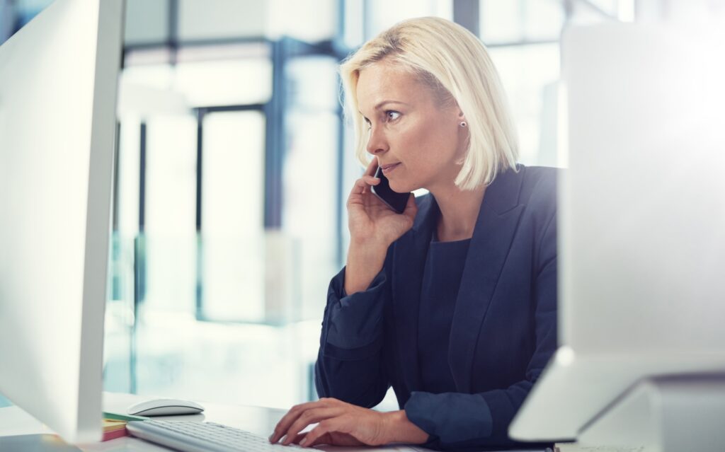Responsable de la communication interne au téléphone devant son ordinateur