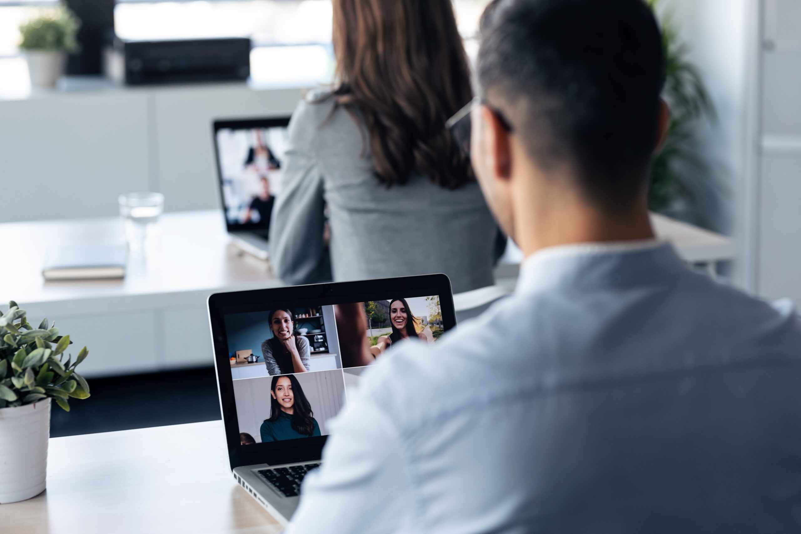 Collaborateurs au bureau en visioconférence avec des collègues en télétravail